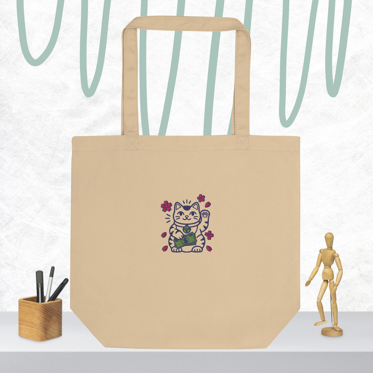 Product mockup of the Hustle Hard Lucky Cat embroidered organic cotton canvas tote bag.